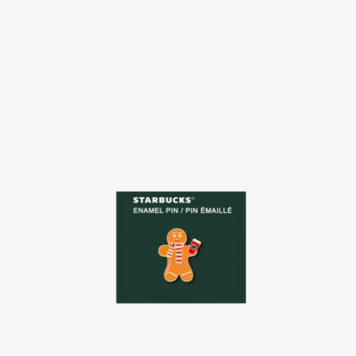 Enamel pin in the shape of a gingerbread man holding a cup, on a dark green card