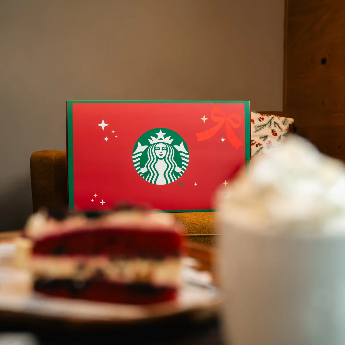 Červený adventní kalendář Starbucks ležící na stole s dezertem a kávou