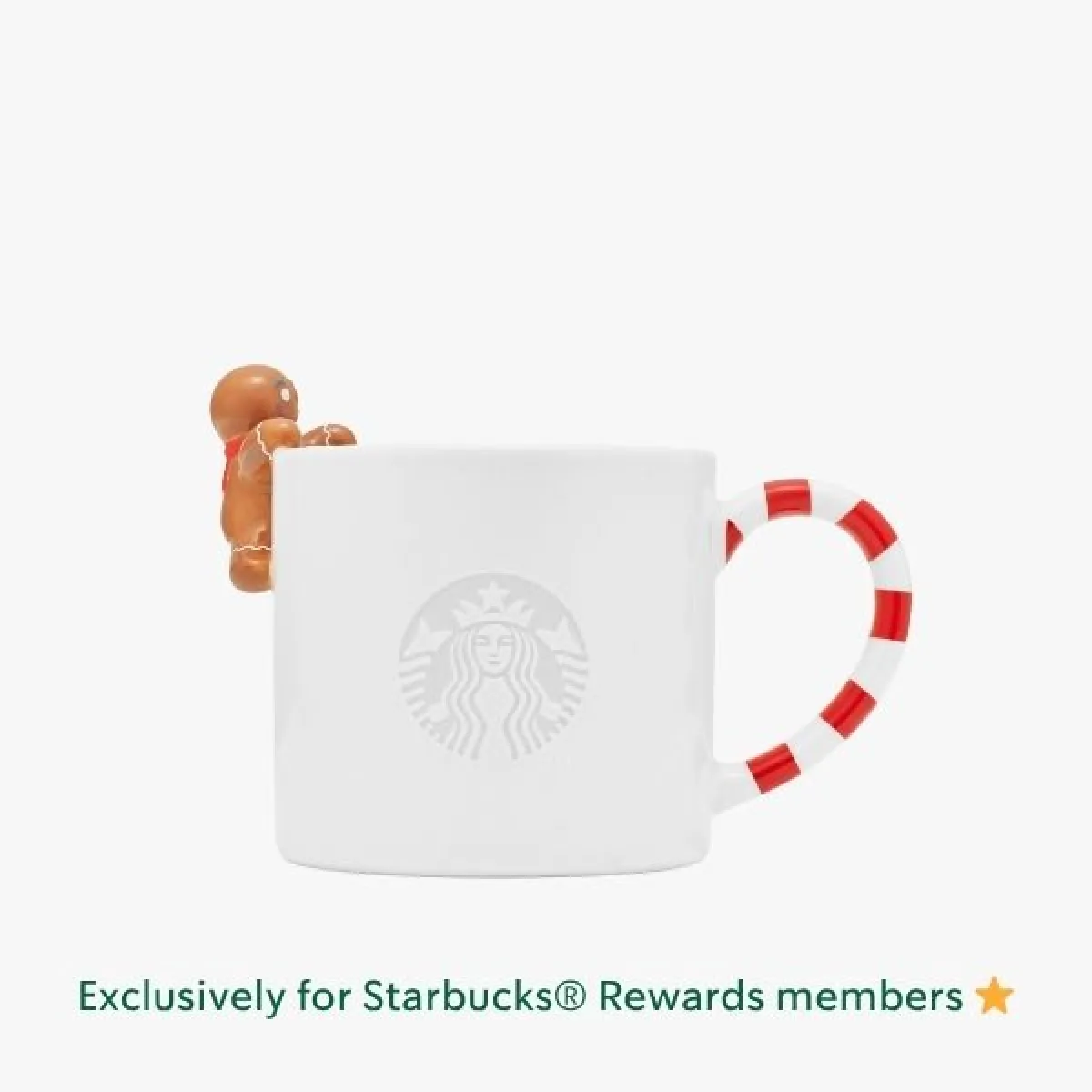 White ceramic mug with a handle shaped like a red-and-white striped candy cane and a small gingerbread man figurine attached to the rim