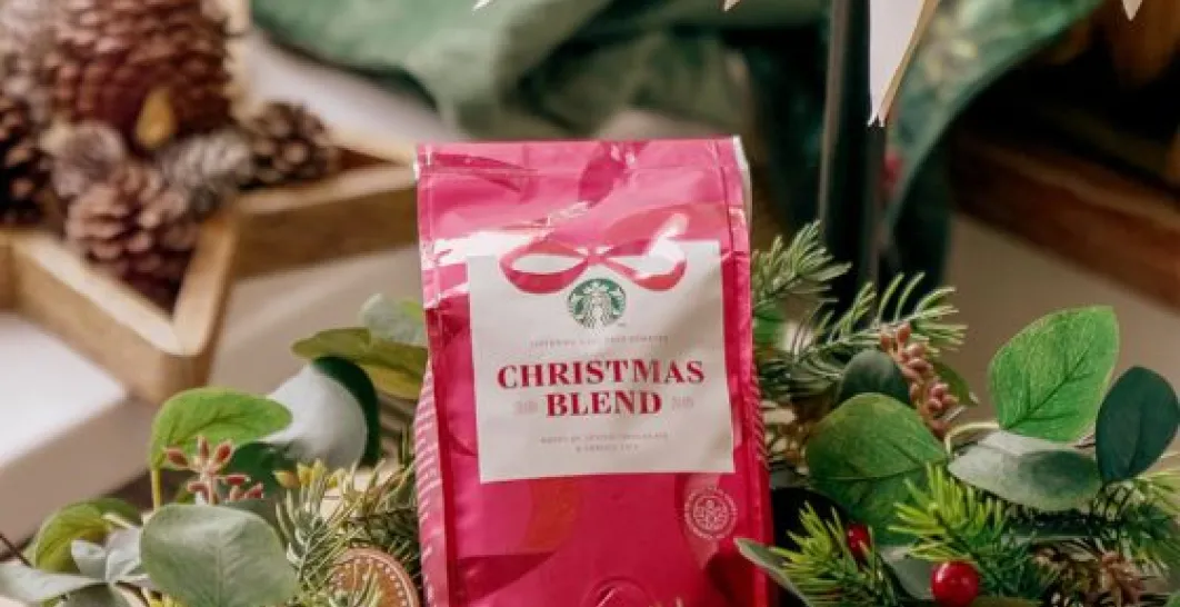 A red bag of Christmas Blend 2025 coffee beans is placed in a green wreath