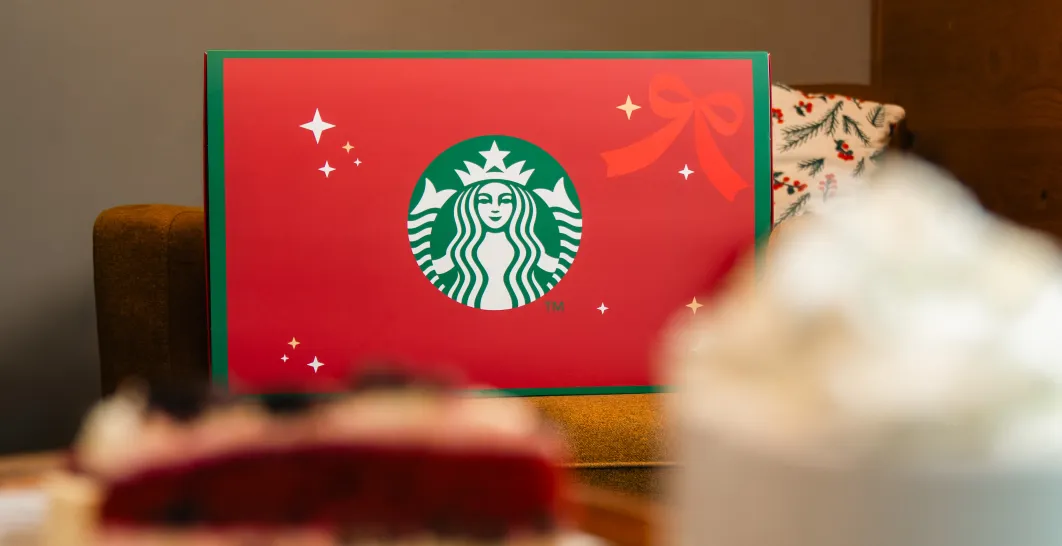 Červený adventní kalendář Starbucks ležící na stole s dezertem a kávou
