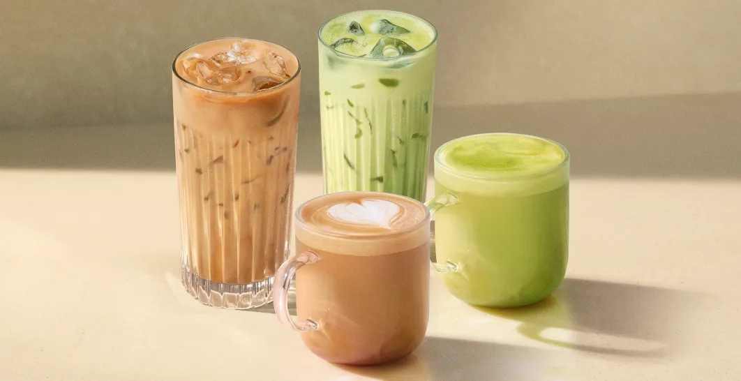 Čtyři nápoje na světlém pozadí, dva teplé ve skleněném hrnku a dva ledové, s ledem ve sklenici s vroubkovaným designem.