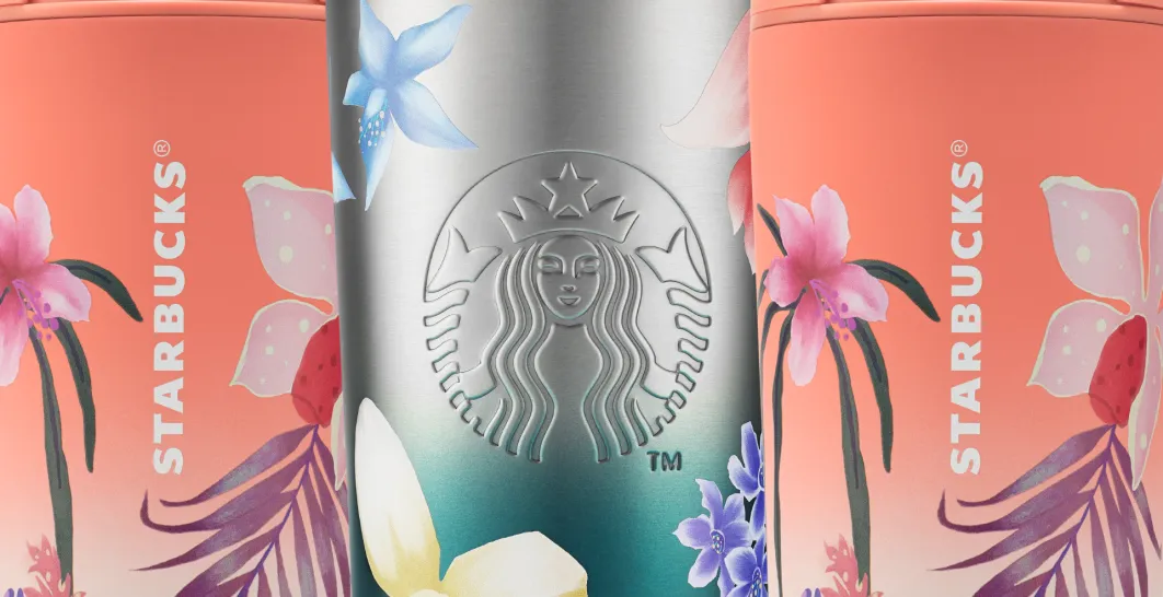 Na obrázku jsou tři znovupoužitelné kelímky Starbucks stojící těsně vedle sebe. Uprostřed je kovově stříbrný kelímek s reliéfním logem Starbucks a tmavě tyrkysovým víčkem, ozdobený jemnými pastelovými květinami. Po levé i pravé straně jsou částečně vidět růžově až korálově zbarvené kelímky s bohatými botanickými motivy a různobarevnými květy. Celek působí dekorativně a elegantně díky kombinaci kovového povrchu a měkkých květinových ilustrací.